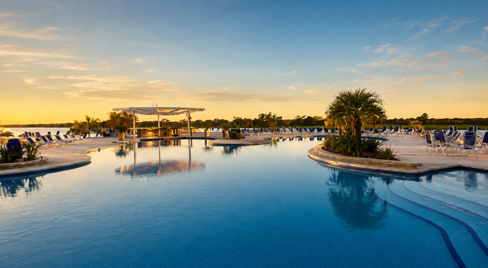 Piscina del club al atardecer con palmeras, bar central y reposeras frente al río Paraguay
