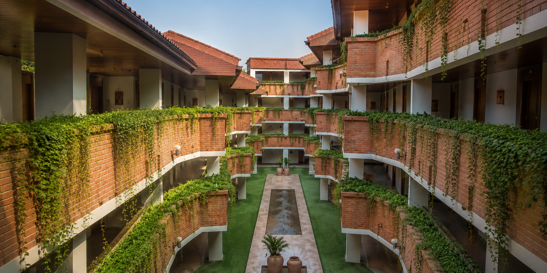 Patio interior del hotel con galerías cubiertas de enredaderas, tejado colonial y jardín central con espejo de agua